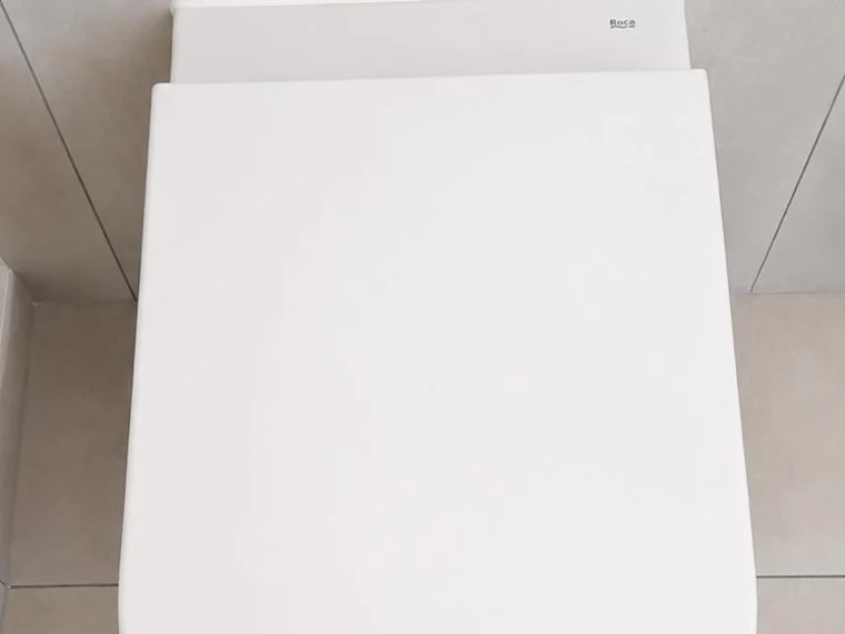 WC suspendu blanc posé contre un mur carrelé clair
